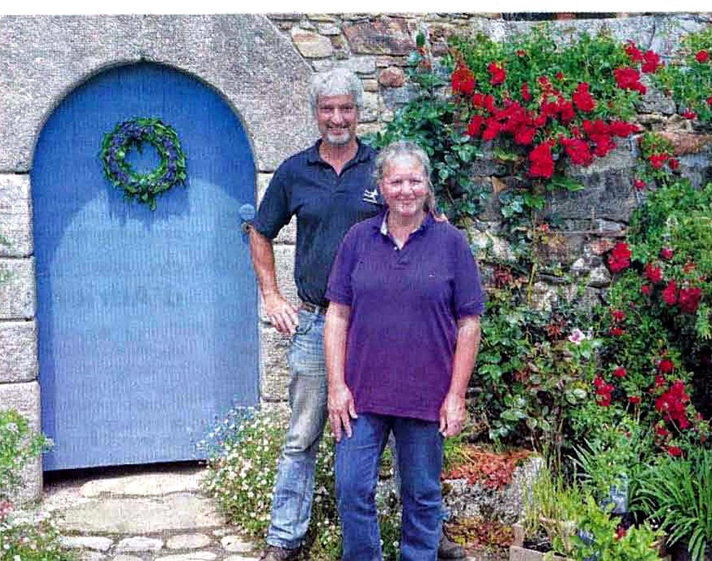 Hanneke et Erwin devant la porte bleue du gîte, sous les rosiers