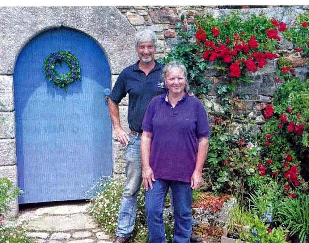 Hanneke et Erwin devant la porte bleue du gîte, sous les rosiers